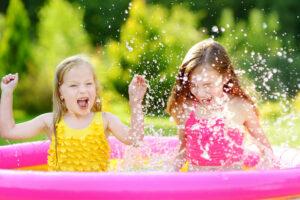 Fröhliche Kinder planschen an heißem Sommertag im Garten Pool.