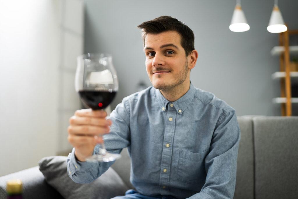 Mann trinkt Rotwein aus einem Glas