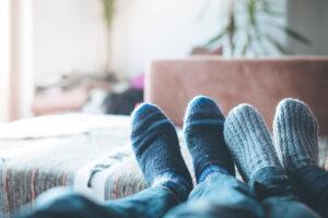 Junges Paar liegt gemütlich auf der Couch, Füße mit Wollsocke