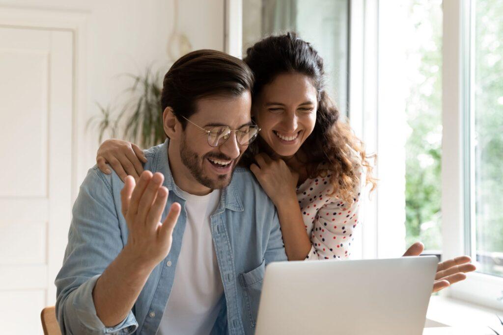 Ein glückliches Paar sitzt vor einem Laptop und freut sich über einen Gewinn beim Lotto Online Tippen. Ihre Freude und Aufregung sind deutlich sichtbar, während sie ihre Erfolge feiern.