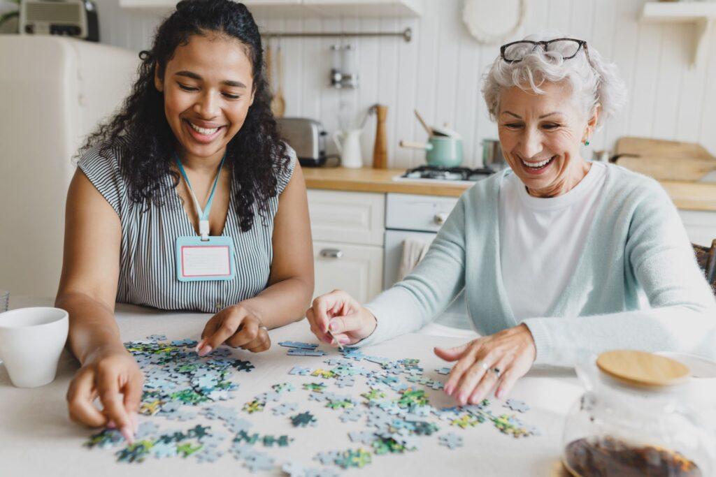 Pflegerin und Seniorin puzzeln gemeinsam in der Küche