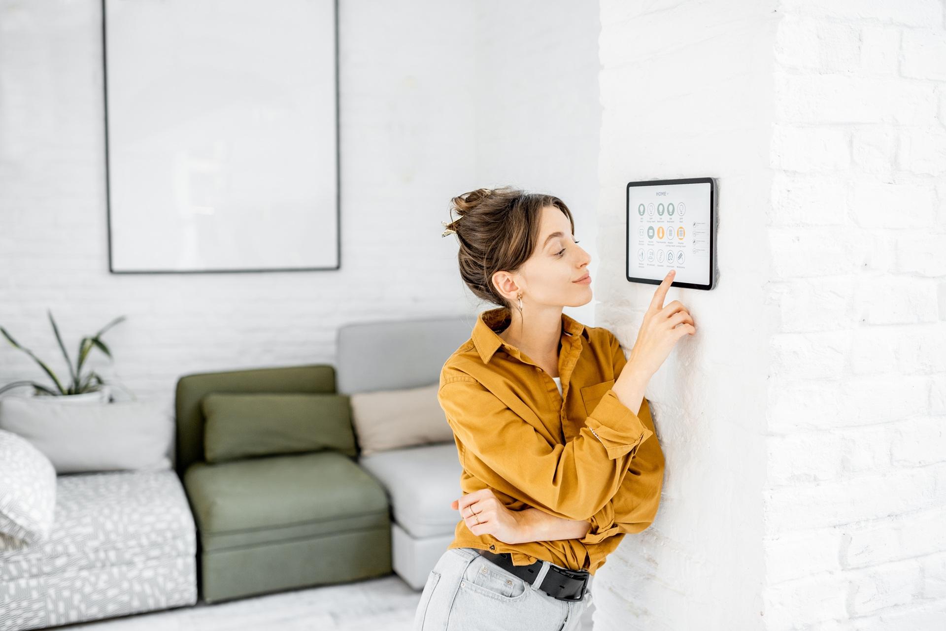 Frau nutzt Smart-Home-Wandpanel | Heizölpreise Sachsen