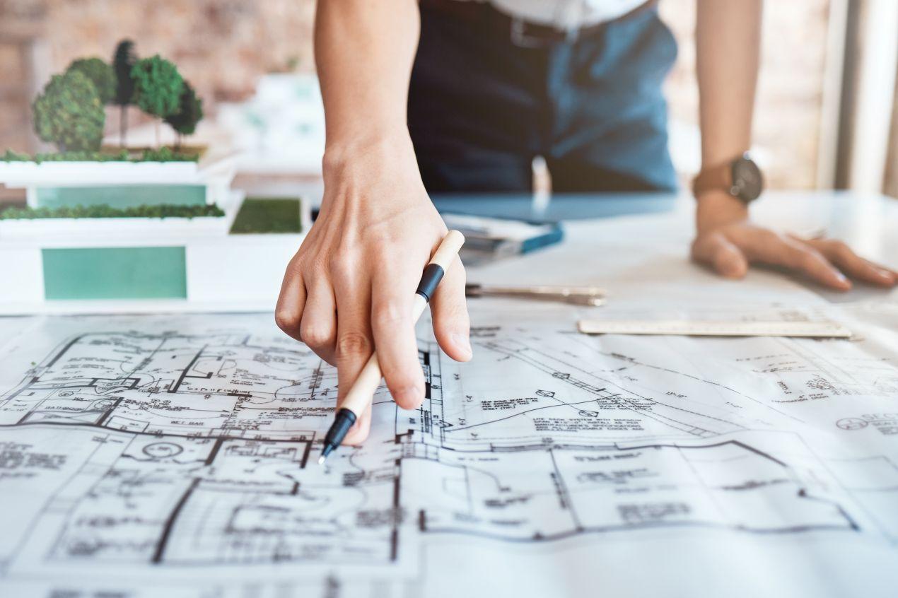 Architekt haelt Stift ueber Bauzeichnung und plant Stauraumkonzept mit Eckkleiderschrank fuer komplexe Grundrisse