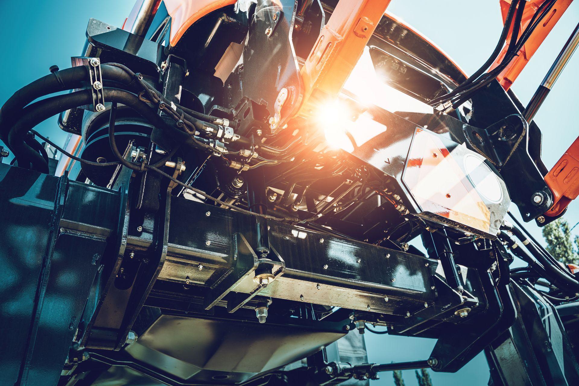Nahaufnahme eines Frontladers mit sichtbaren Hydraulikschläuchen und Zylindern – technische Ansicht einer hydraulischen Gerätebetätigung